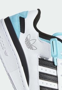 Sneaker bianco con strisce nere, dettagli blu e pelle texturizzata. Presenta un logo prominente e un collare imbottito per il comfort.