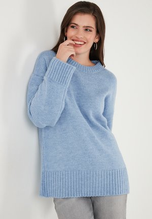Pull en maille bleu clair avec des poignets et un ourlet côtelés. Coupe ample et texture douce, avec un col large et des épaules tombantes.