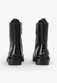 Stivaletti neri alla caviglia con finitura matte liscia e accenti lucidi. Presenta una zip laterale e un tacco basso e testurizzato.