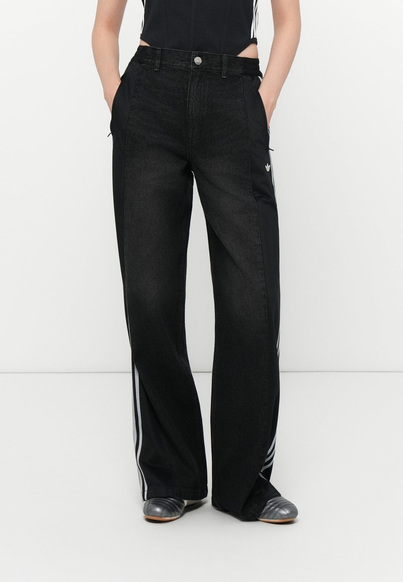 Svarta vida byxor med en denimframsida och släta svarta tygsidor, accentuerade med tre vita ränder och fickor.