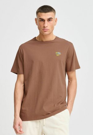 Braunes Baumwoll-T-Shirt mit Rundhalsausschnitt, kurzen Ärmeln und einem kleinen, bunten Logo auf der linken Brust. Glatte Textur, lässige Passform.