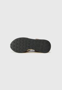 Rubber outsole with a textured, patterned surface, featuring squares and rectangles. Upper section blends brown and white tones.