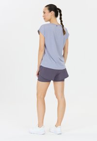 Ljust blå randig kortärmad topp tillsammans med mörkgrå träningsshorts. Modellen bär vita sneakers och visar upp en avslappnad sportoutfit.