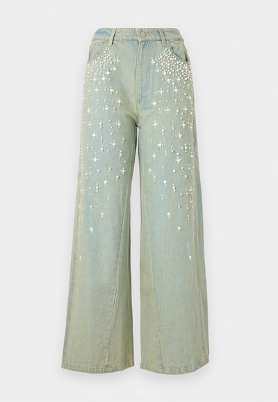 Plačia kojų blauzdžių džinsai šviesiai mėlyno džinso audinio. Kišenėse ir priekyje puošiami kalnų krištolo akutėmis. Aukštu liemeniu, standartiniu mygtuko užsegimu.