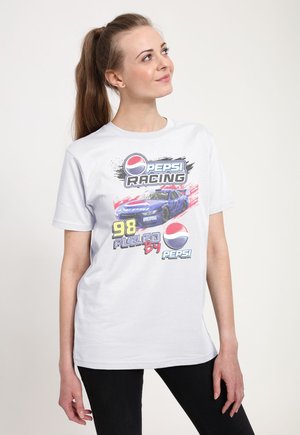 Vrouw met lange paardenstaart draagt wit Pepsi Racing T-shirt met blauwe raceauto, nummer 98 en Pepsi-logo's op een lichte achtergrond.