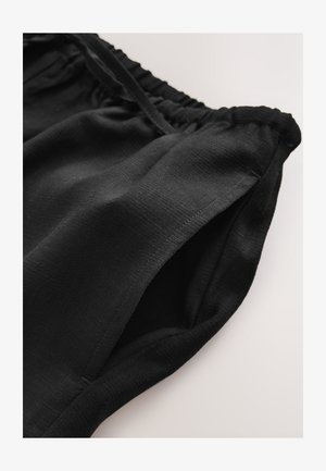 Schwarze Shorts mit elastischem Bund aus leichtem Stoff, mit glatter Textur und umgeschlagenem Saum. Keine sichtbaren Muster oder Beschläge.