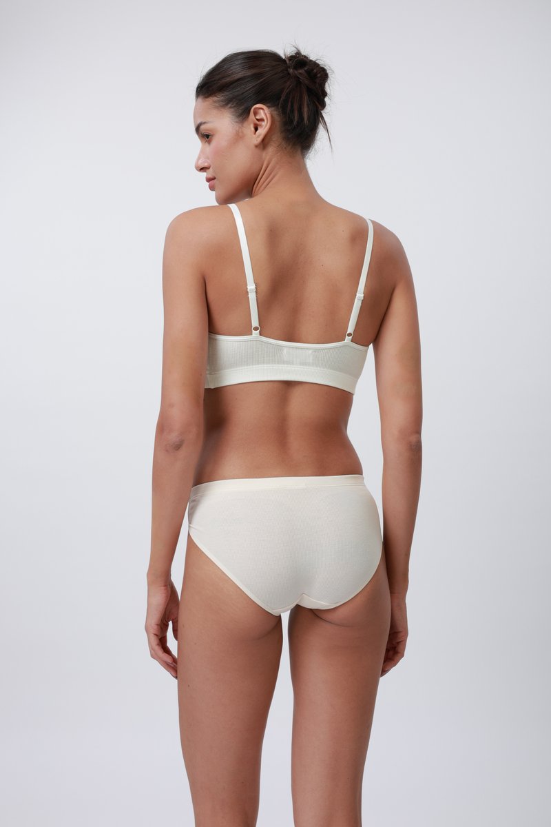 Soutien-gorge en tissu beige clair côtelé avec des bretelles réglables, assorti à des culottes hipster sans coutures, mettant en valeur une texture lisse et un design simple.