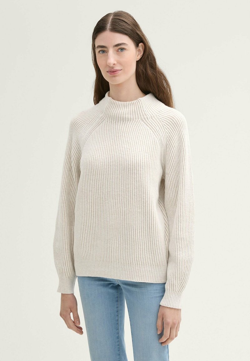 Beige gerippter Pullover mit hochgeschlossenem Kragen, langen Ärmeln und lockerer Passform. Weicher Stoff und dezentes Lichtmuster durchgehend.