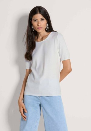 Hellgrauer Pullover mit kurzen Ärmeln, rundem Ausschnitt und geripptem Saum, kombiniert mit hellblauen Jeans mit weitem Bein. Glatte Strickstruktur.