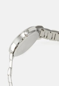 Reloj de acero inoxidable plateado con una caja redonda, acabado pulido y pulsera de eslabones. Presenta una corona texturizada marcada como "BOSS."
