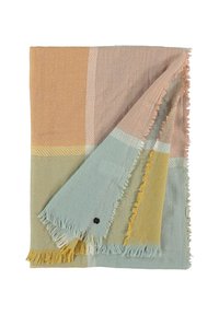 Couverture en plaid pliée avec des bords à franges dans des blocs pastel atténués de pêche, bleu clair, jaune moutarde et beige sur fond blanc.