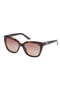 Lunettes de soleil en écaille de tortue foncée avec de grandes lentilles dégradées, une monture épaisse et des accents en métal sur les branches, arborant un design angulaire chic.