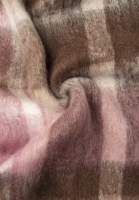 Couverture en laine à carreaux présentant une texture douce avec des teintes de brun, rose et crème, affichant un motif à carreaux et des plis délicats.