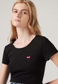 Black short-sleeve T-shirt in a fitted design, featuring a small red Levi's logo on the front near the neckline. Soft cotton material.