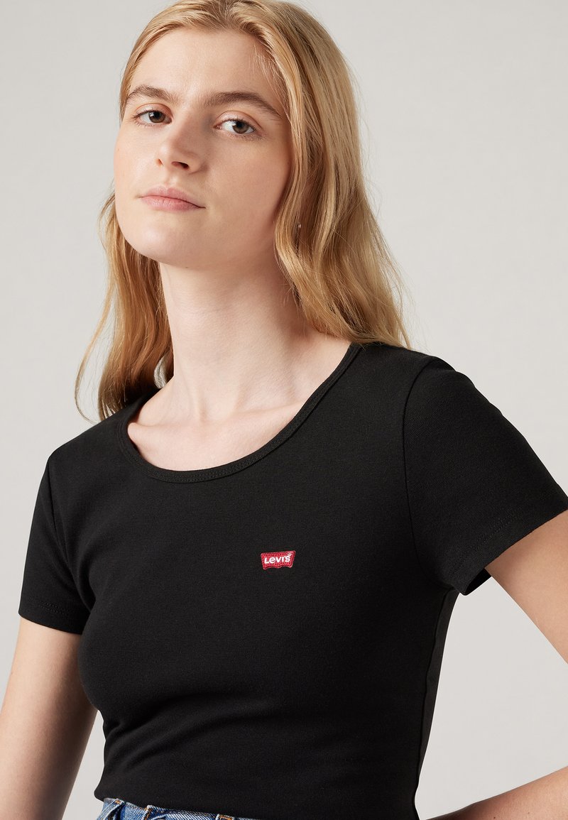 T-shirt noir à manches courtes au design ajusté, avec un petit logo rouge Levi's à l'avant près du col. Matière en coton doux.