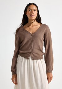 Gilet en tricot marron avec un col V, des manches longues et une fermeture à boutons à l'avant. Texture douce, taille cintrée et tissu lisse.