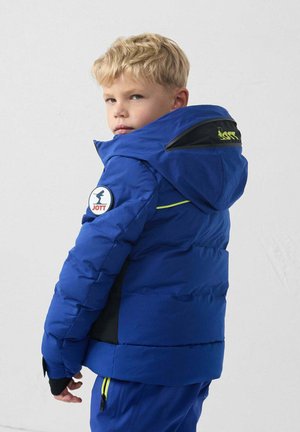 Blue padded jacket with a hood, featuring black accents, a round logo patch on the sleeve, and yellow zipper detailing.