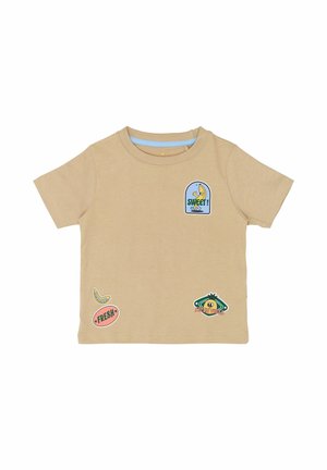 Bež pamučna majica kratkih rukava s višebojnim zakrpama: banana, plava etiketa s natpisom "SWEET!" i razni grafički prikazi.