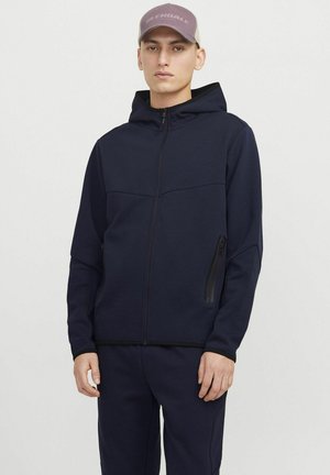 Navy zip-up hoodie made of soft fabric, featuring a hood, front zip pocket, and black accents along the zipper and cuffs.