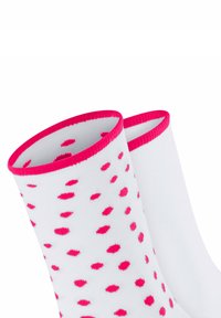Weiße Knöchelsocken mit rosa gerippten Bündchen, verziert mit verstreuten rosa Punkten. Weiches Strickmaterial mit einer glatten Textur.