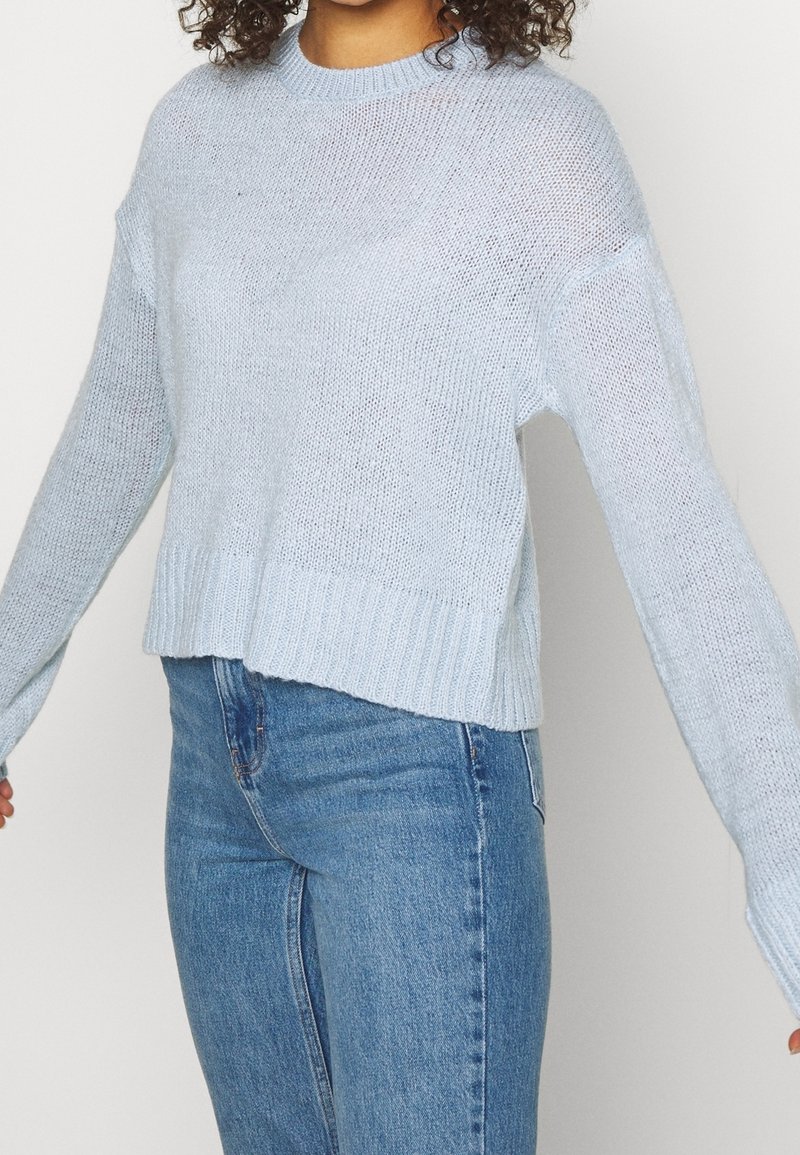 Hellblauer gestrickter Pullover mit langen Ärmeln, geripptem Saum und lockerer Passform. Hergestellt aus einem weichen, leichten Material mit einer atmungsaktiven Textur.