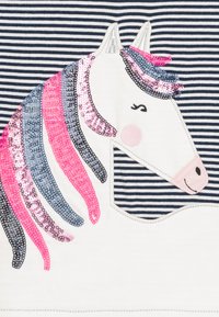 Baumwollstoff mit marineblauen und weißen Streifen; mit Pailletten besticktes Einhorn-Motiv in Pink, Grau und Silber; glatte Textur mit gesteppten Akzenten.