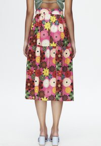 Floral midi-rok van meerkleurige stof met grote madelief en bloempotjespatronen, met een gelaagde ontwerp en een aansluitende tailleband.
