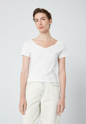 Camiseta blanca de manga corta con un diseño de cuello en V, fabricada en tela de algodón. Forma simple y ajustada con una textura suave.