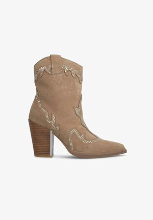 Beige suède cowboy laarzen met een spitse neus, gedetailleerde stiksels en zilveren studaccenten. Heeft een gestapelde bruine hak en decoratieve uitsparingen.