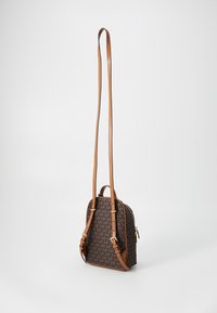 Zaino marrone con motivo e accenti marrone chiaro, chiusura con zip e spallacci regolabili. Presenta una maniglia superiore e hardware color oro.