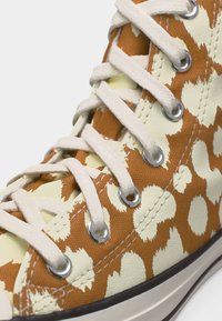 Υψηλό καμβά πάνινο παπούτσι με κρεμ και πορτοκαλί αφηρημένο πουά σχέδιο, λευκά κορδόνια, μεταλλικά οφθαλμίδια και λευκή ελαστική σόλα.