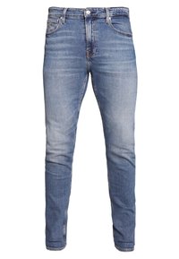 Sittande blå denimjeans med ljus tvätt, med fem fickor, bälteshällor och dragkedja. Tyget har ett slätt, strukturerat utseende.