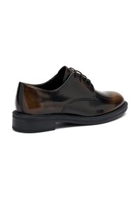 Scarpe eleganti in pelle nera e marrone con una finitura liscia, punta rotonda, design con lacci e una suola piatta e ampia. Gradiente di colore delicato.
