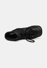 Schwarze Stiefel bis zur Wade mit gesteppter Textur, aus Nylon, runder Zehenform und kontrastierenden goldenen Beschlägen für das Schnüren und die Anpassungen.