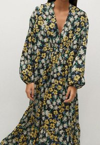Kukkaprinteininen maxi-mekko pitkillä hihoilla, jossa on syvä V-pääntie, kootun vyötärön ja laivastonsininen tausta, jossa on keltaisia ja valkoisia kukkia.