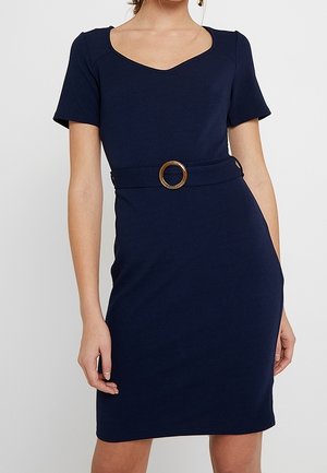 Granatowa dopasowana sukienka z krótkimi rękawami, dekoltem w szpic oraz paskiem z okrągłą złotą klamrą, wykonana z gładkiej tkaniny.