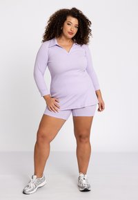 Lavendel Sportset, bestehend aus einem langärmeligen Poloshirt mit V-Ausschnitt und passenden, figurbetonten Shorts, aus dehnbarem Stoff.