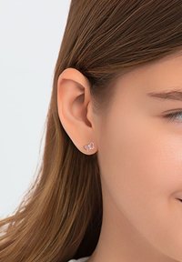 Rosa Schmetterlings-Ohrringe mit Silberakzenten, die an einem Ohr präsentiert werden. Das Design verfügt über sanfte Kurven und eine glatte Oberfläche.