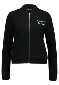 Zwarte zip-up jas met "too cool to care" geborduurd op de bovenste linkerborst, met ribgebreide kraag, cuffs en zoom.