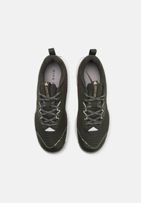 Tummanvihreät urheilukengät, joissa on teksturoitu päällinen, kontrastiväriset harmaat nauhat, valkoiset yksityiskohdat ja kumipohja, suunniteltu polkujuoksuun.