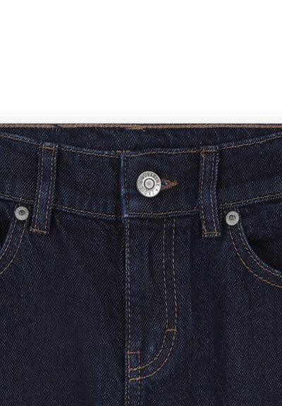 Jean en denim bleu foncé avec une fermeture à bouton, poches standard et couture contrastante. Texture lisse avec un léger motif de tissage diagonal.