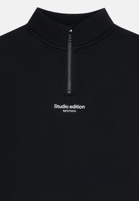 Sudadera negra con cremallera de cuarto y texto blanco "Edición de estudio 55°57'03"N" centrado debajo de la cremallera en el pecho.