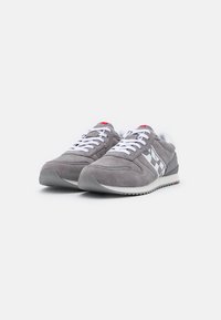 Gray suede sneakers with white laces, a white lining, and a side checkered pattern. Features a white midsole and textured gray outsole.