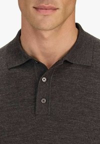 Tummanharmaa polo-paita, joka on valmistettu teksturoidusta kankaasta. Siinä on klassinen kaulus, kolme napin läpivientiä ja hienovaraisia ompelutukia.