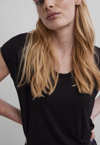 Svart t-skjorte med korte ermer og avslappet passform, med rund halsutskjæring. Stoffet ser mykt ut med en jevn tekstur.