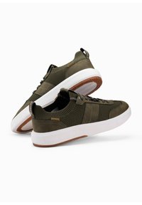 Zapatillas verdes con parte superior de malla, acentos de ante texturizado, una entresuela blanca y una suela de goma marrón, con detalles de costura en contraste.