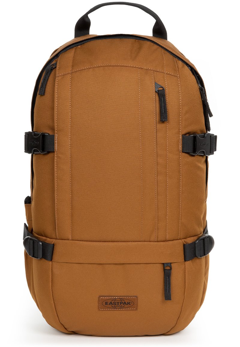Zaino in tessuto marrone con design strutturato, dotato di spallacci regolabili, manico superiore, hardware nero e due tasche laterali.