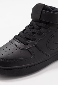 Sapatilhas mid-top pretas feitas de couro liso, com solas de borracha texturizada, bico perfurado e pespontos e atacadores tonais.