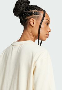 Krémově zbarvený oversized svetr s volným střihem, měkkou texturou a kulatým výstřihem. Obsahuje jednoduchý design a jemné švy.