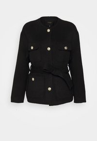 Veste noire à manches longues avec encolure ronde, quatre poches à rabat à l'avant, boutons dorés et ceinture nouée à la taille.